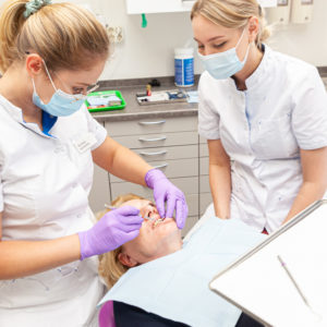 Tandarts en assistent voeren wortelkanaalbehandeling uit bij de patiënt bij ontstoken tandvlees